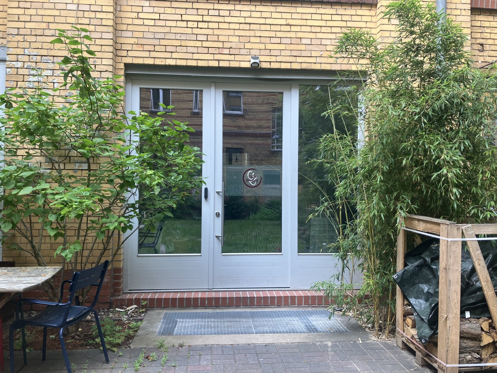 The CCB Studios entrance: a glass door in the second courtyard at Hasenheide 12, surrounded by bamboo and greenery.