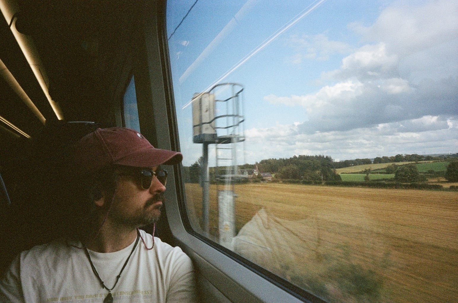 Tim looking out the window of a train at passing fields.